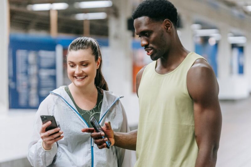 Två åersoner på gym som tittar i telefonen